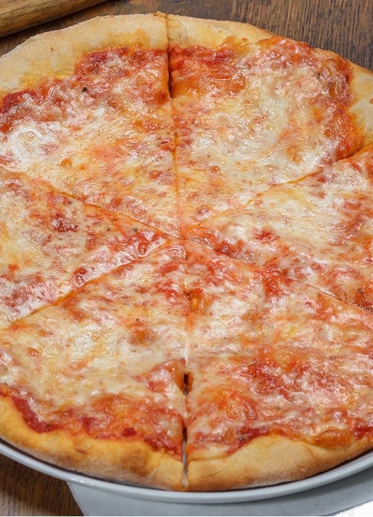 A classic cheese pizza with a golden-brown crust, sliced into eight pieces, topped with melted mozzarella cheese and tomato sauce, served on a silver tray over a wooden table.